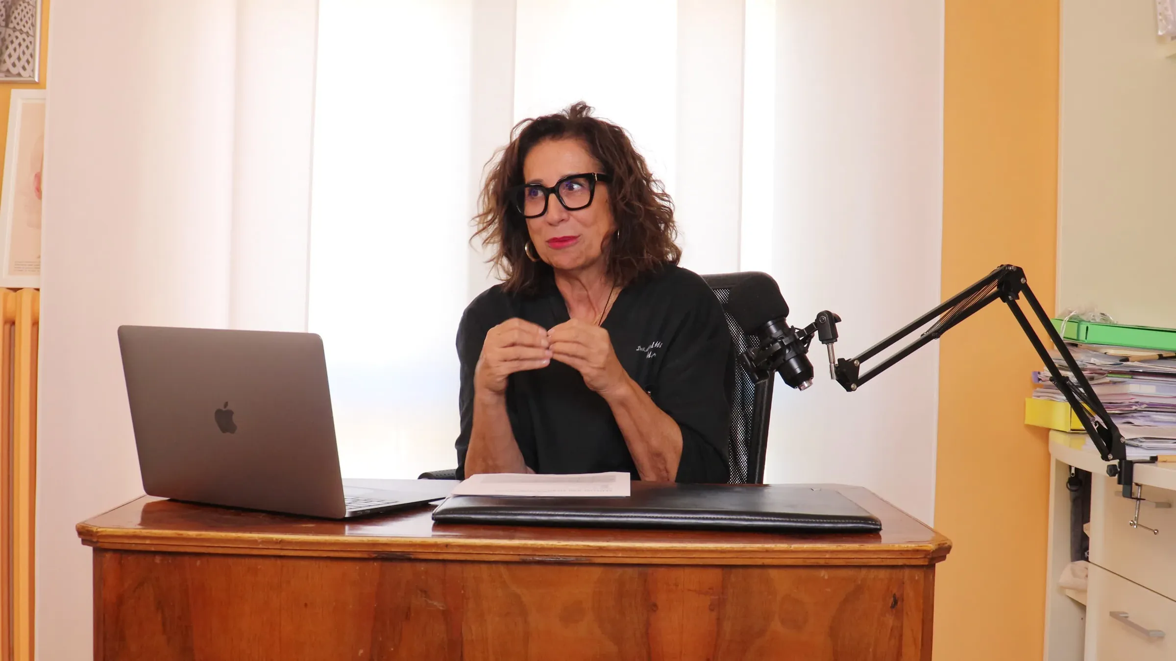 La Dott.ssa Paola Molinari alla sua scrivania durante le riprese, con microfono e computer